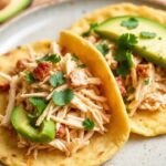 Golden arepa pocket filled with shredded chicken and avocado.