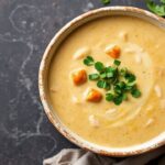 Creamy Tortilla Soup topped with chicken, cilantro, and crispy tortilla strips.
