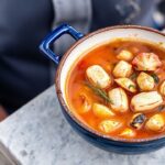 Rich bouillabaisse, saffron-infused Marseille fish stew, steaming in bowl.